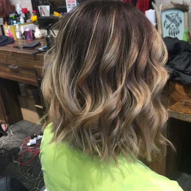 back view of medium messy bob hairstyle with highlights