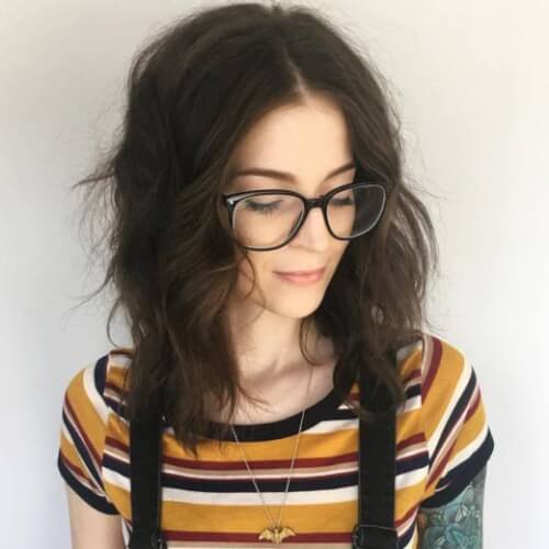 A girl with glasses who has a remarkable dark shoulder-length cut and color
