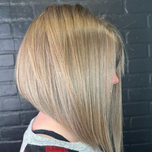 Graduated Long Bob - a woman wearing a gray shirt and in a black brick wall