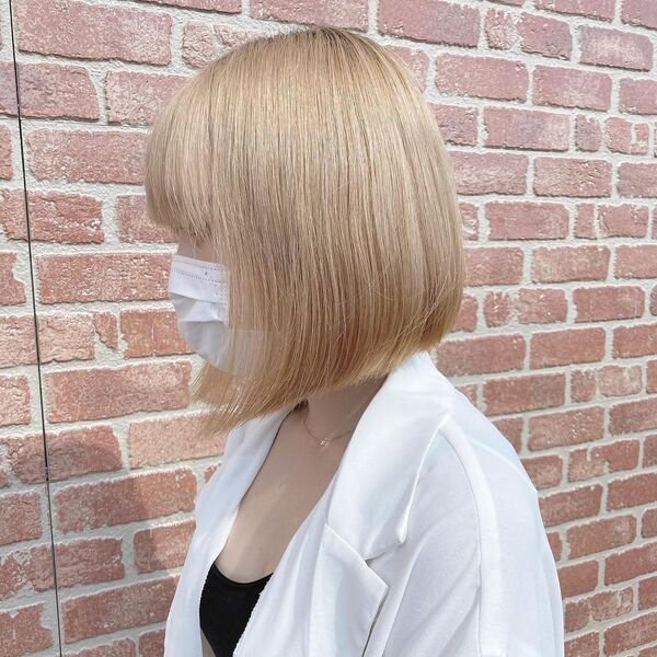 Light Blonde Oguno Bob - a woman wearing a white polo shirt and white mask