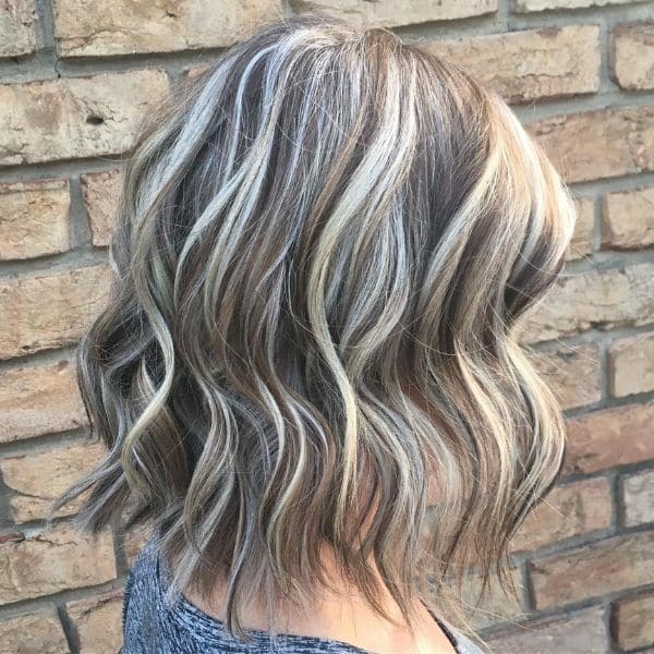 wavy bob - woman wearing faded gray shirt with a brick wall background