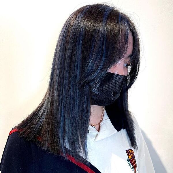 a woman wearing a black facemask has a subtle blue hair