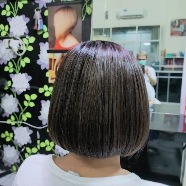 Ash Brown with Silver Highlight - a woman facing a mirror wearing a white shirt