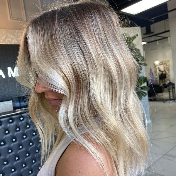 Beige Ash Blonde - a woman in a salon wearing a white sleeveless shirt