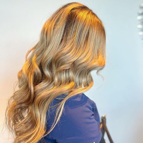 Bright and Golden Blonde Balayage - a woman wearing a dark blue shirt