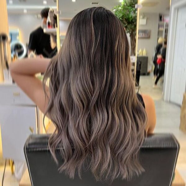 brown peekaboo hair - a girl seating and touching her hair wearing sleeveless black shirt