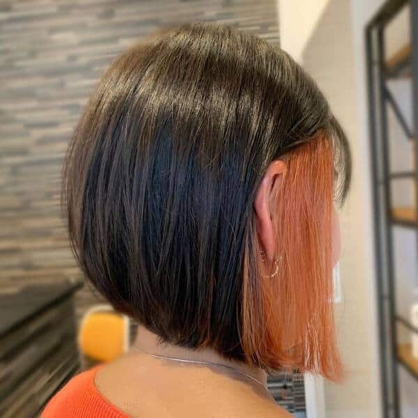 brown peekaboo hair - a woman wearing orange shirt and has an earrings