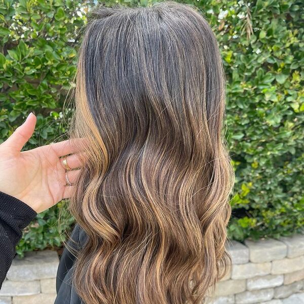 Brunette Melt Blonde Balayage - a woman wearing a black shirt and another woman is holding her hair