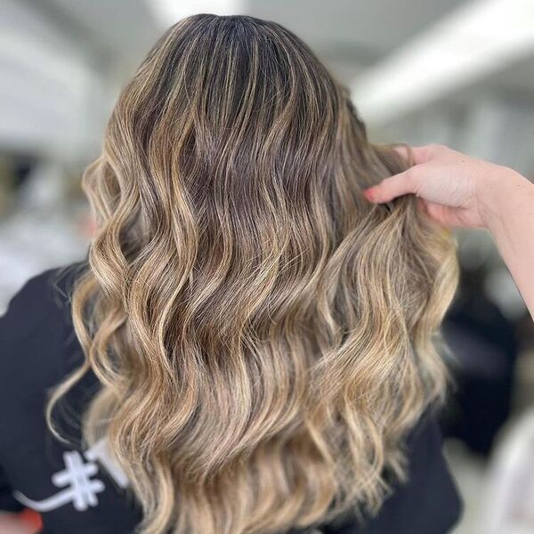 Caramel Blonde Balayage - a woman wearing a black shirt and a woman is holding her hair