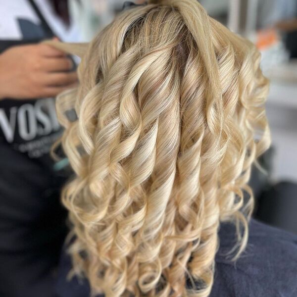 Curly Light Ash Blonde - a woman wearing a salon black towel and a person holding her hair