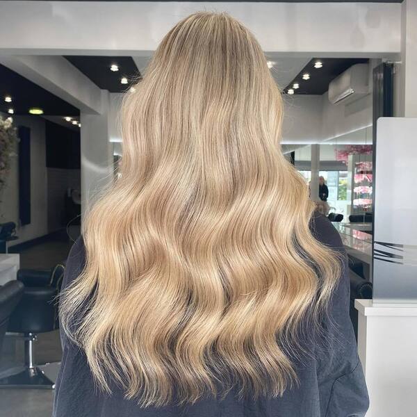 dark blonde hair - a woman inside a salon wearing a black cape