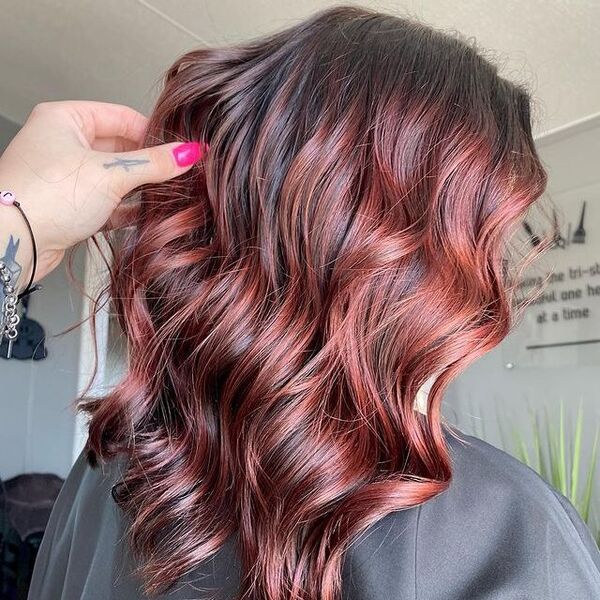 dark red hair - a girl wearing a black barber's cape with someone holding her hair