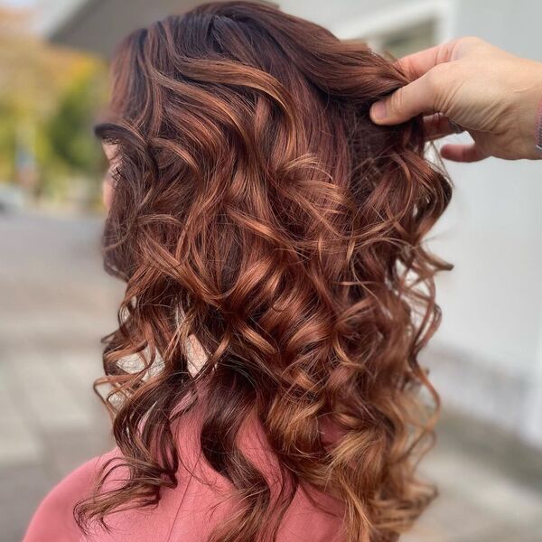 Flattering Red Brown in Loose Curls - a woman wearing a peach shirt.