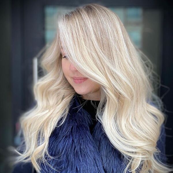 Flawless Oak Blonde Balayage - a woman slightly smiling is wearing a thick fur coat