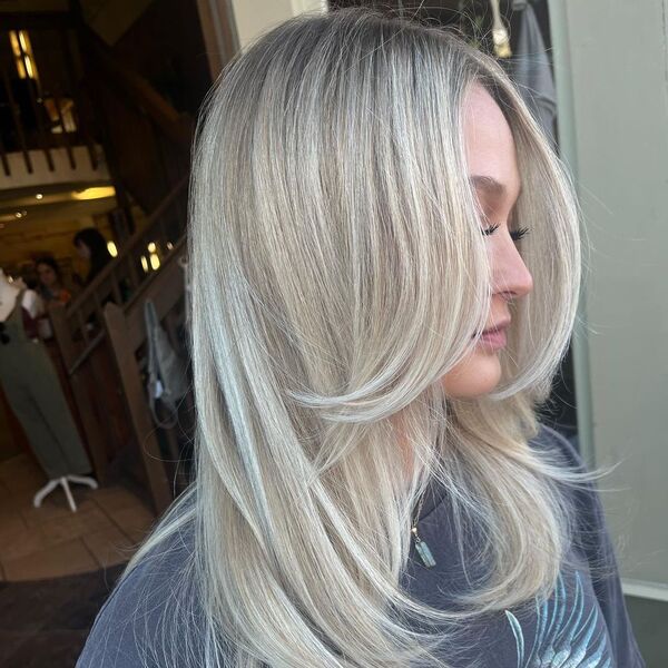 Fresh Cut Full Blonde Balayage - a woman wearing a dark blue shirt and has a long eyelash