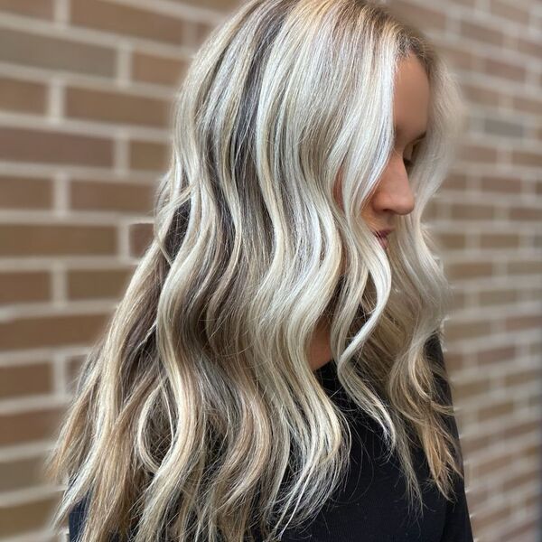 Icy Blonde Balayage - a woman near brick wall is wearing a black shirt