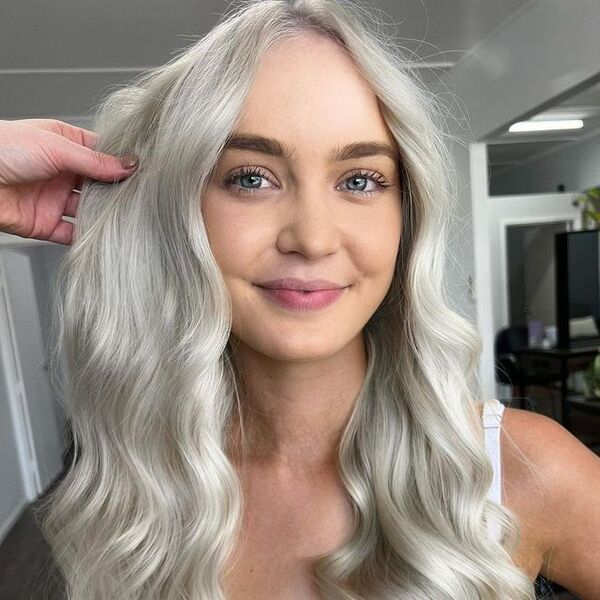 Icy White Bombshell Blonde Hair - a woman wearing a green top