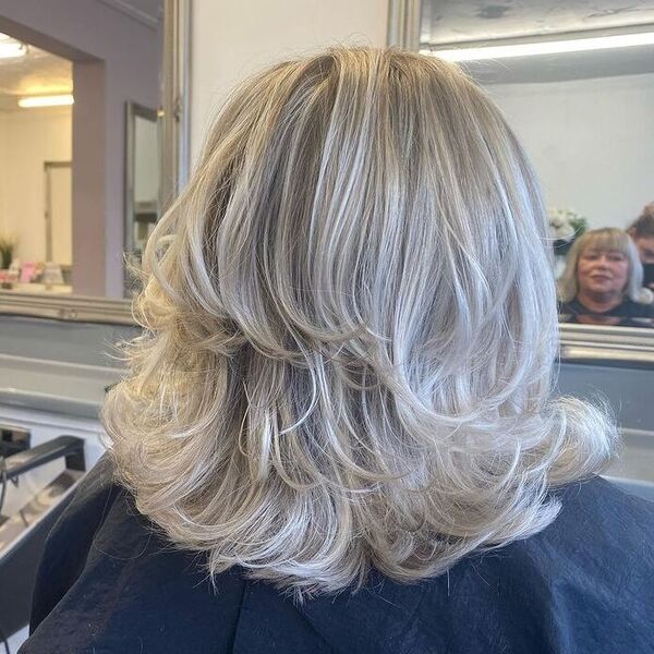 Layered Silver Flicks - a woman facing a mirror and is wearing a black cape