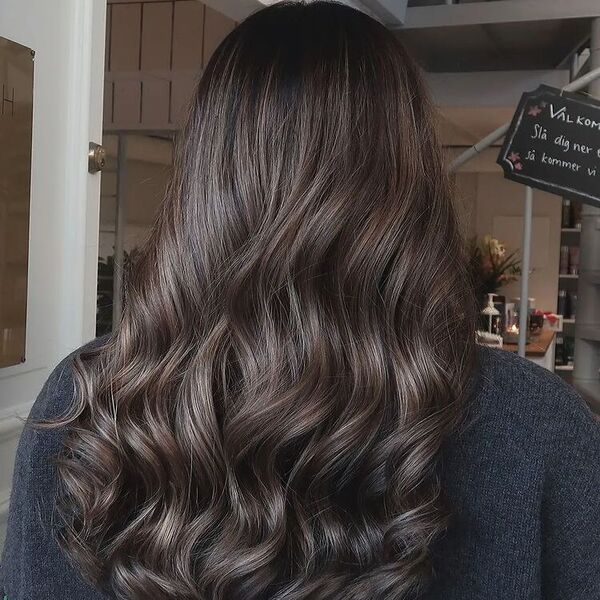 Lengthy Umber Balayage on Dark Hair Curls - a woman wearing dark blue sweater.