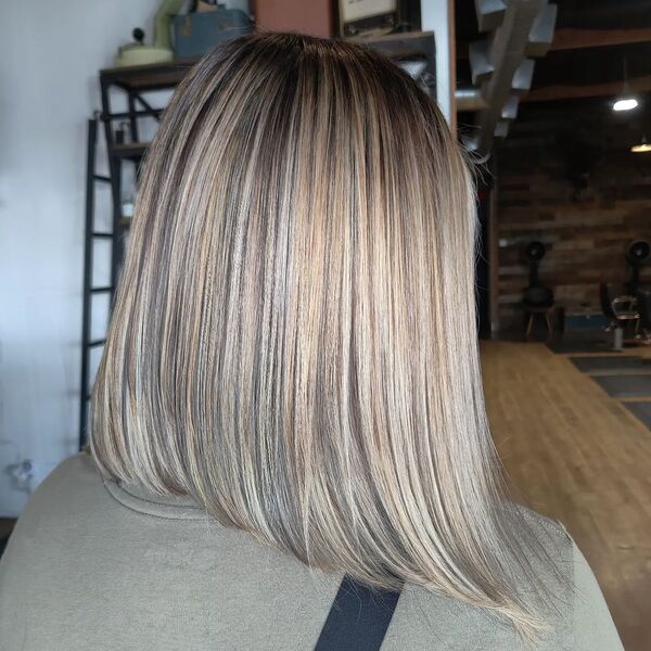 Perfect Platinum Blonde A-line Bob - a woman wearing an army green shirt and a black strap