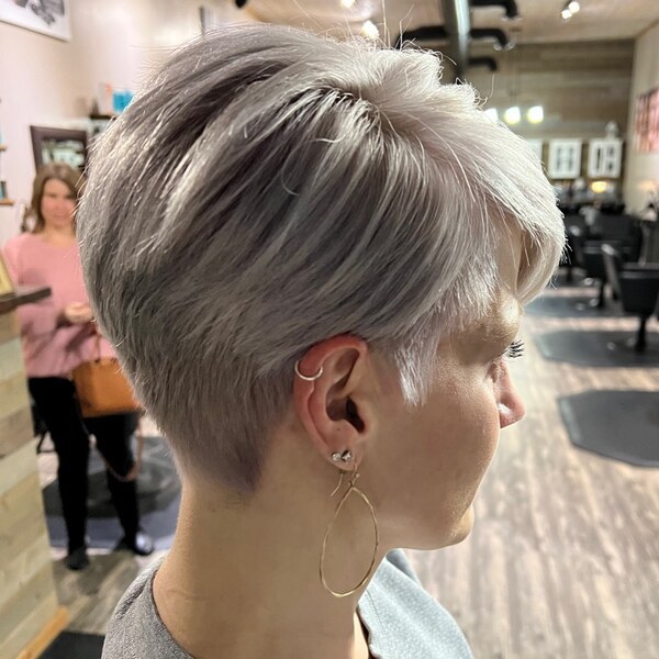 Platinum Pixie with a Fun Undercut - a woman wearing a gray shirt and multiple earrings