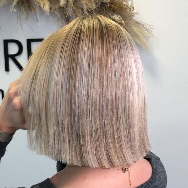 Short Bob Platinum Ash Blonde - a woman wearing a gray sweater