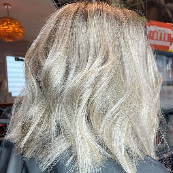 Soft Ash Blonde Balayage - a woman wearing a black cape