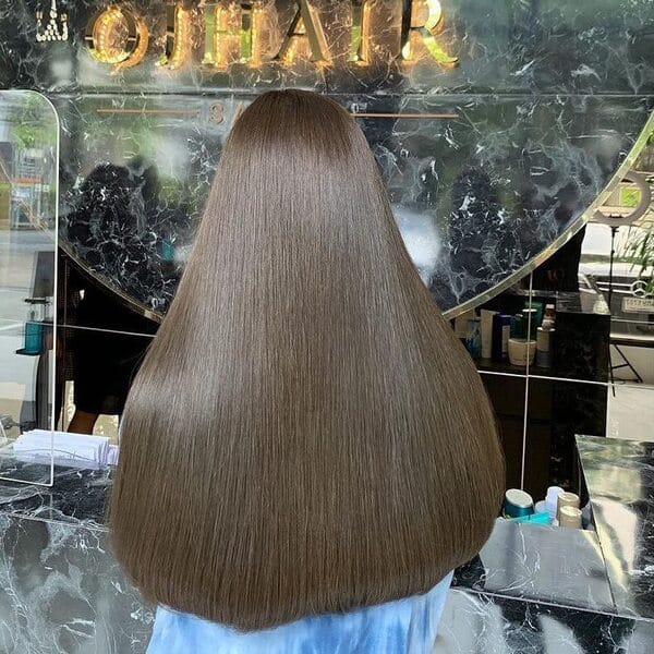 Straight Hair Ash Brown - a woman in a salon wearing a blue top