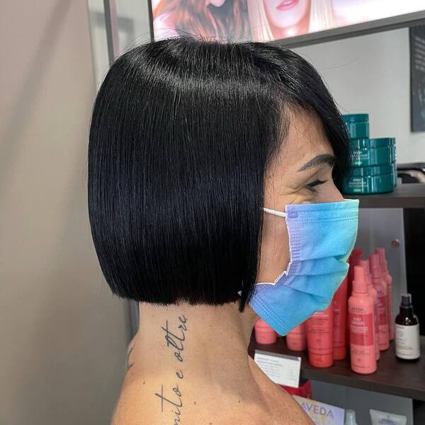 Super Short Bob with Black Blue Hair - a woman with tattoos is wearing a facemask