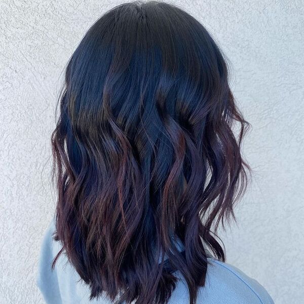 Syrup Balayage with Loose Curls - a woman wearing pastel blue blouse.