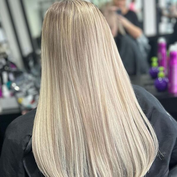 Vanilla Ash Blonde - a woman wearing a black salon's cape