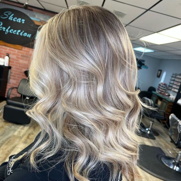 Vanilla Bean Blonde Balayage - a woman in a salon wearing a black shirt