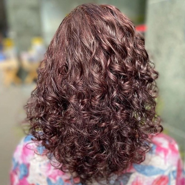 Volume Spring Curls in Red Brown - a woman wearing tie-dyed bright shirt.