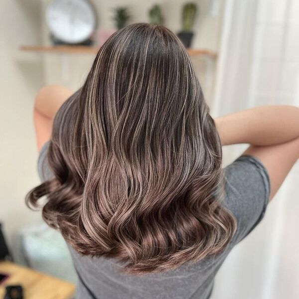 Wavy Dark Ash Blonde - a woman wearing a gray shirt and is holding her hair