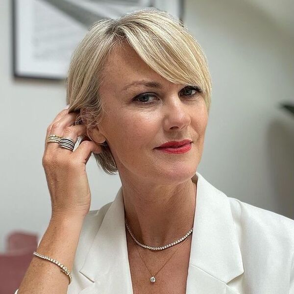 a woman wearing a beautiful necklace has chin-length blonde bob with side bangs