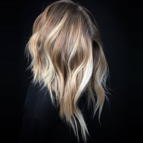 a woman wearing a black blouse has a long inverted bob wavy hair