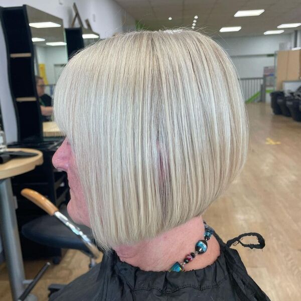 a woman wearing a black cape has a platinum graduated bob