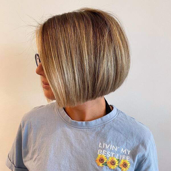 a woman wearing a blue printed shirt with natural short blonde bob