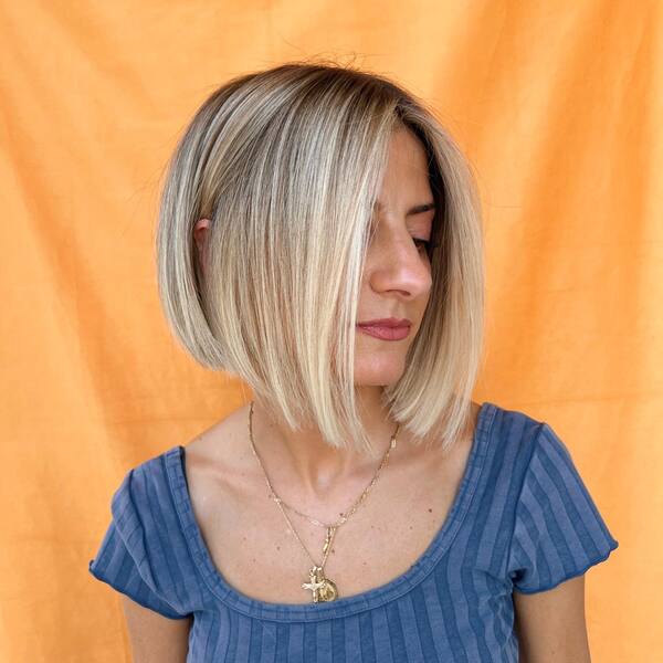 a woman wearing a blue top with short a-line blonde bob hair