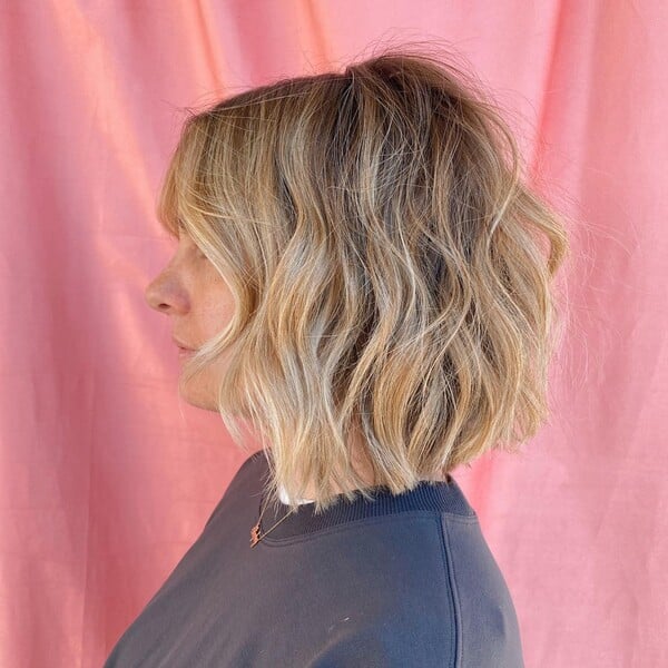 a woman wearing a dark blue shirt with honey blonde with waves hair