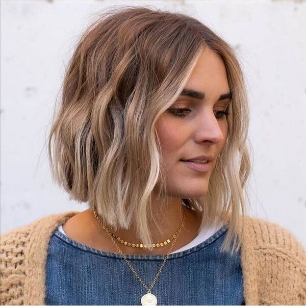 a woman wearing a gold necklace with angle bob haircut