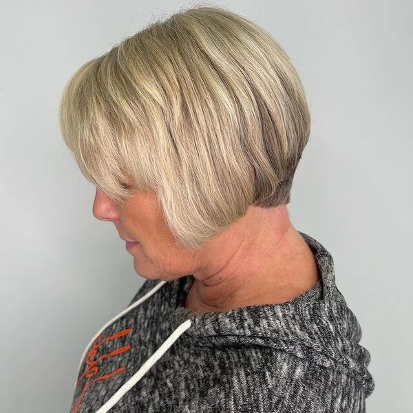 a woman wearing a gray hooded blouse has a graduated bob hairstyle