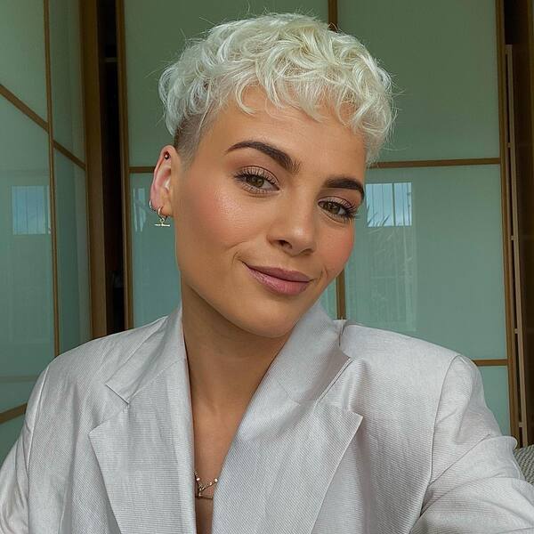 a woman wearing a white longsleeve with platinum pixie with side cut