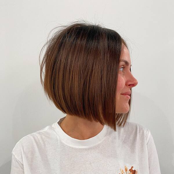 a woman wearing a white shirt with dark brown blonde hair