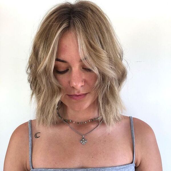 A woman with a necklace wearing a gray sleeveless shirt