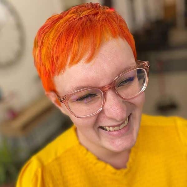 Bright Edgy Pixie with Small Bangs - a woman wearing yellow top