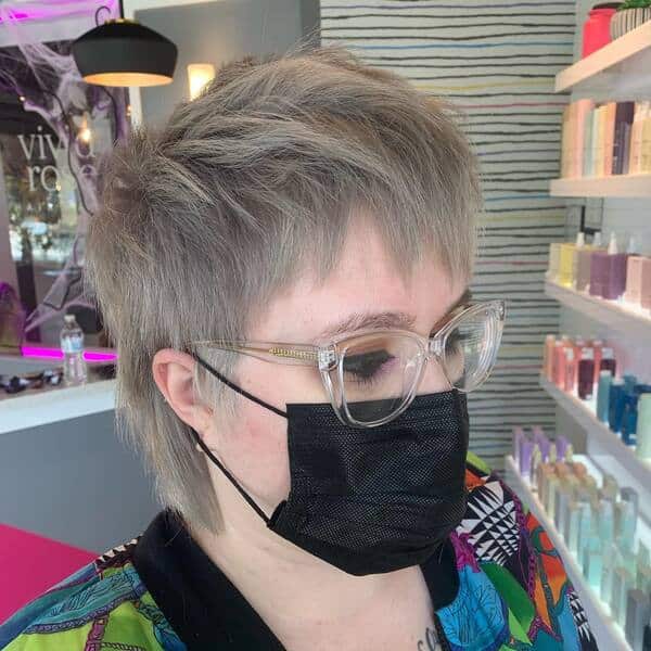 Edgy Ash Pixie Mullet: una mujer con una chaqueta colorida y una máscara