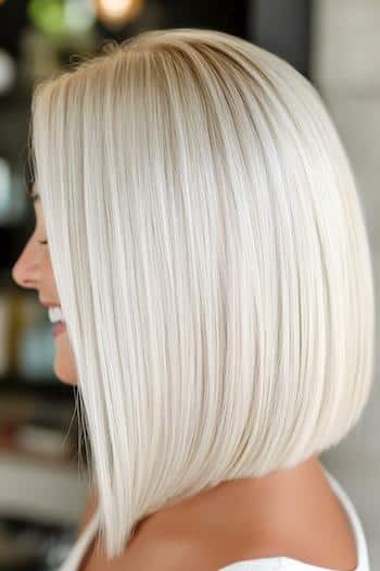 32 coupes de cheveux au carré lisse pour un look moderne Coupe de cheveux Platinum Blunt Long Bob sur une femme souriante aux cheveux blonds platine, vue de côté.