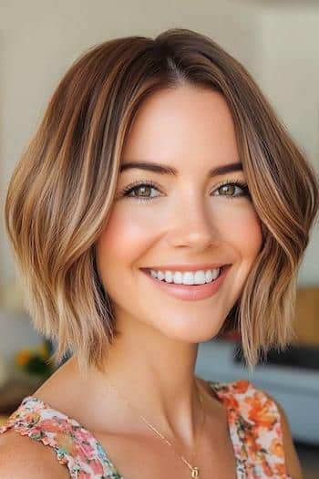 32 coupes de cheveux au carré lisse pour un look moderne Coupe de cheveux Bob ondulée douce sur une femme souriante aux cheveux bruns et aux mèches.